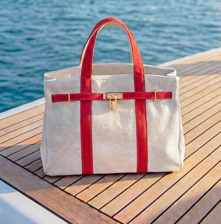 boatkin bag with red straps and a gold lock set on a yacht deck