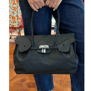 Black jelly firkin bag with glossy finish, top handles, and front lock detail
