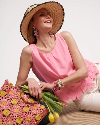 Woman in pink top with straw hat and bag