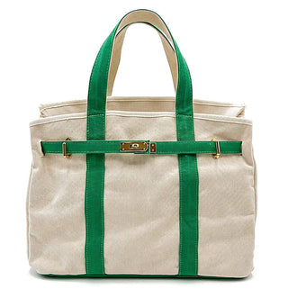 A canvas tote bag in beige with prominent green straps and trim, featuring a gold-tone turn-lock closure on the front strap, set against a plain white background.