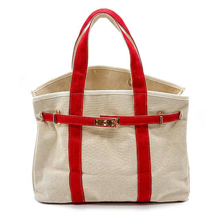 A canvas tote bag in beige with vibrant red handles, side panels, and a matching red front strap featuring a gold-tone turn-lock clasp, shown against a plain white background.