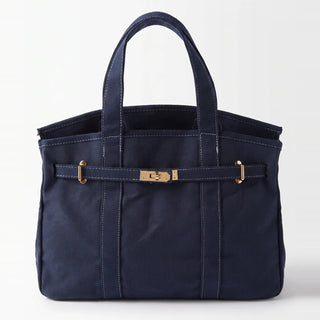 A navy blue canvas tote bag with double top handles, vertical stitched panel lines, and a front strap closure featuring gold-tone hardware.